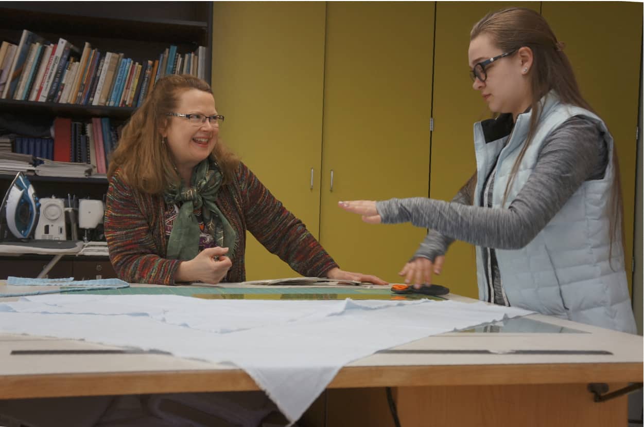 professor ann braaten assists student with designs