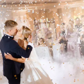 Posrtrait of tenderness couple, bride with groom kissing while falling confetti and enjoying celebration of wedding day, wearing in beautiful dress and suit.